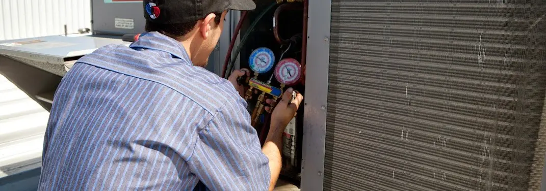 HVAC technician servicing a condenser unit in Wilmington